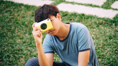 Young man photographing with camera on field