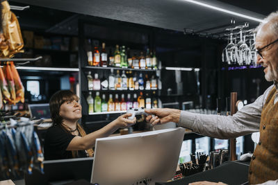 Young saleswoman giving game controller to male customer at gaming lounge