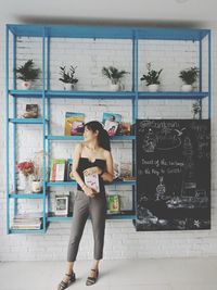 Full length of young woman standing against wall