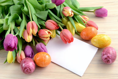 Close-up of tulips and greeting card with easter eggs on table