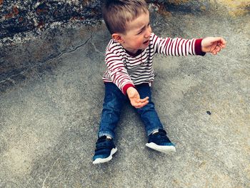 High angle view of boy crying while sitting on footpath