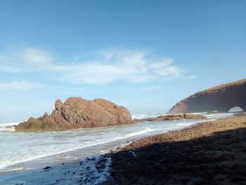 Rock formations on beach against sky