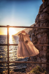 Clothes hanging on rock by sea against clear sky