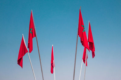 Low angle view of flags against clear blue sky