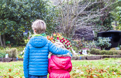 Siblings standing against flowers in graveyard