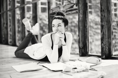 Thoughtful woman lying on hardwood floor