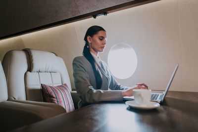 Businesswoman using laptop in airplane