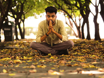 Portrait of man sitting on leaves during autumn