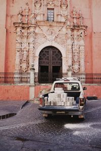 Bricks in pick-up truck on street outside historic building