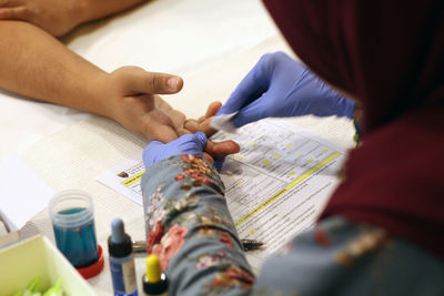 Cropped hands of doctor removing blood sample from patient finger