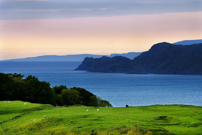 Scenic view of lake by mountains against sky during sunset