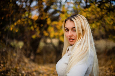 Portrait of young woman standing against trees