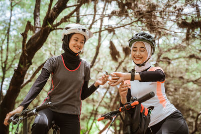 Smiling female friends checking time at park