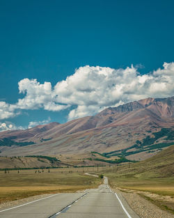 Road leading towards mountains against sky