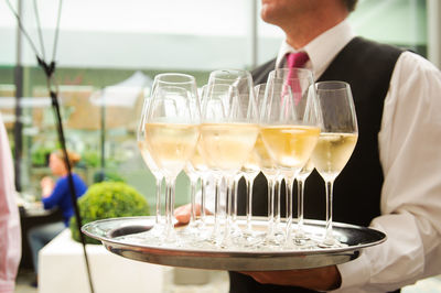 Midsection of waiter with wineglasses at restaurant