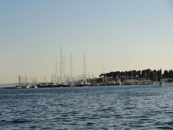 Sailboats in marina at harbor against clear sky