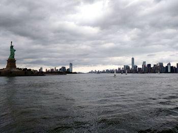 City at waterfront against cloudy sky