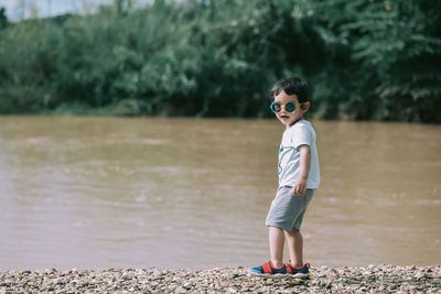 Boy standing on the beach of the river. portrait of young man standing in lake