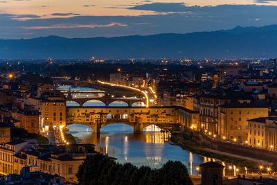 Illuminated bridge over river in city against sky at night