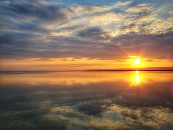 Scenic view of sea against dramatic sky during sunset