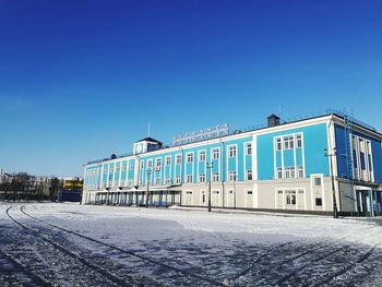 Building by street against clear blue sky in winter