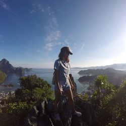 Woman standing on rock looking at mountains against sky