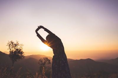 Silhouette person standing by tree against sky during sunset