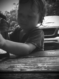 Cute boy looking away while sitting on wood