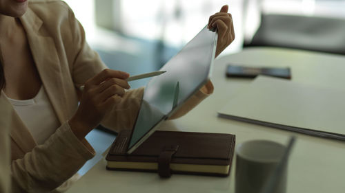 Midsection of businesswoman using digital tablet at desk in office