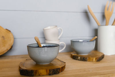 Ceramic tureen with a wooden spoon on a sawn wooden stand in the kitchen in the scandinavian style
