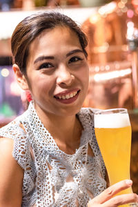 Portrait of smiling woman holding beer glass at restaurant