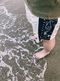 Low section of man standing at beach