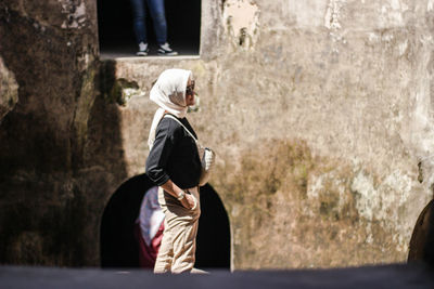 Full length of woman sitting against historic building