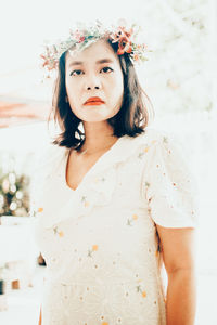 Portrait of young woman standing against wall