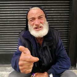 Close-up portrait of senior man sitting against shutter