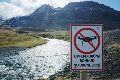 Close-up of information sign board by lake against mountains at snaefellsnes peninsula