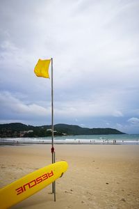 Yellow flag on beach against sky