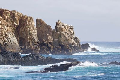 Rock formation in sea against clear sky