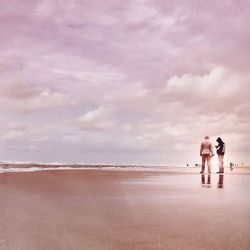 Woman standing on beach against cloudy sky