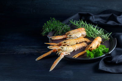 High angle view of lobsters and herbs in plate on table