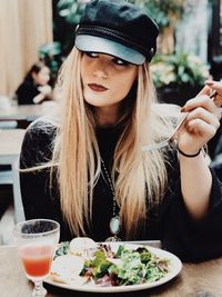 Close-up of young woman with drink sitting on table