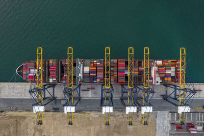 Aerial top view of crane loanding cargo container to container ship in the international terminal