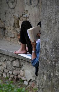 Low section of man sitting on wall