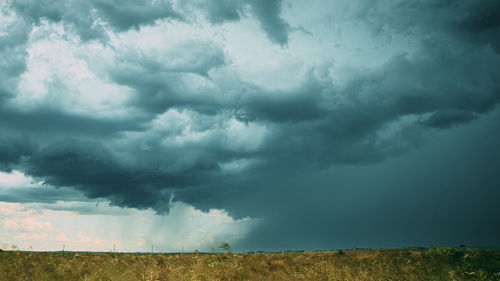 Scenic view of agricultural field against cloudy sky