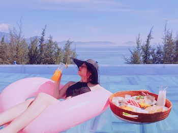 Midsection of woman sitting on table against sky