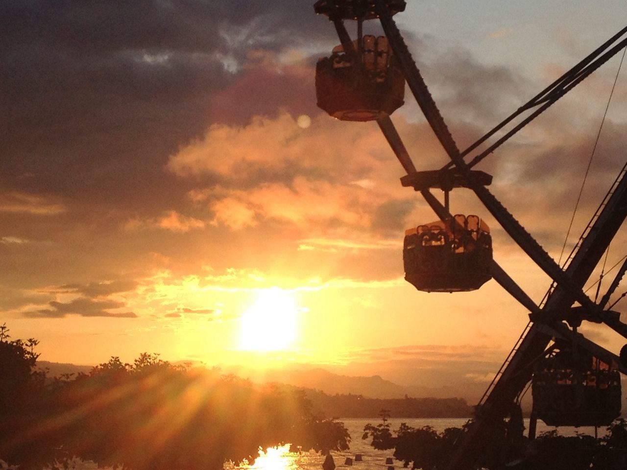 sunset, sky, sun, orange color, cloud - sky, silhouette, low angle view, sunlight, sunbeam, built structure, transportation, nature, metal, crane - construction machinery, mode of transport, cloud, outdoors, cloudy, architecture, lens flare