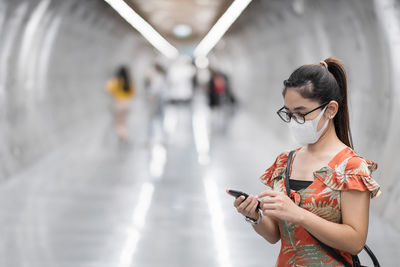 Young woman using mobile phone while standing at camera