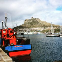 Fishing boats moored at harbor against sky