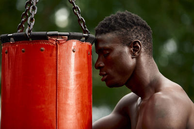 Side view of shirtless man standing against blurred background