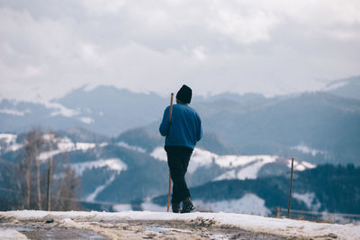 Rear view of man standing on mountain during winter